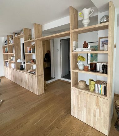Étagères en bois clair avec des objets de décor et des livres sur un sol en bois.